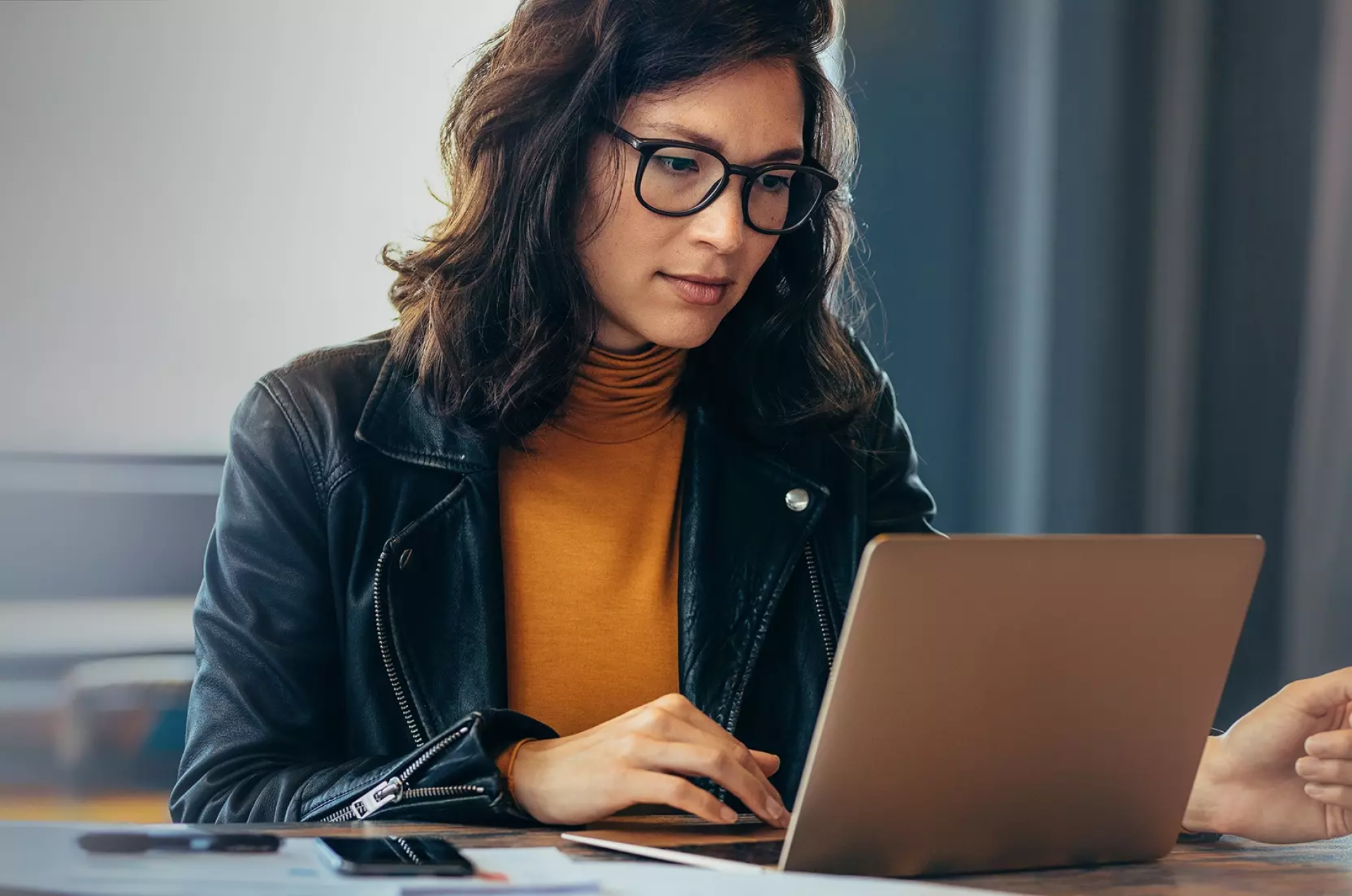 Vrouw met bril werkt geconcentreerd op laptop.