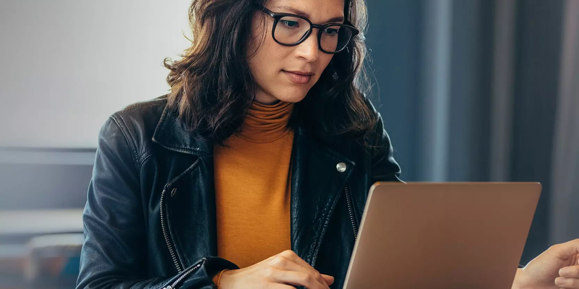 Vrouw met bril werkt geconcentreerd op laptop.