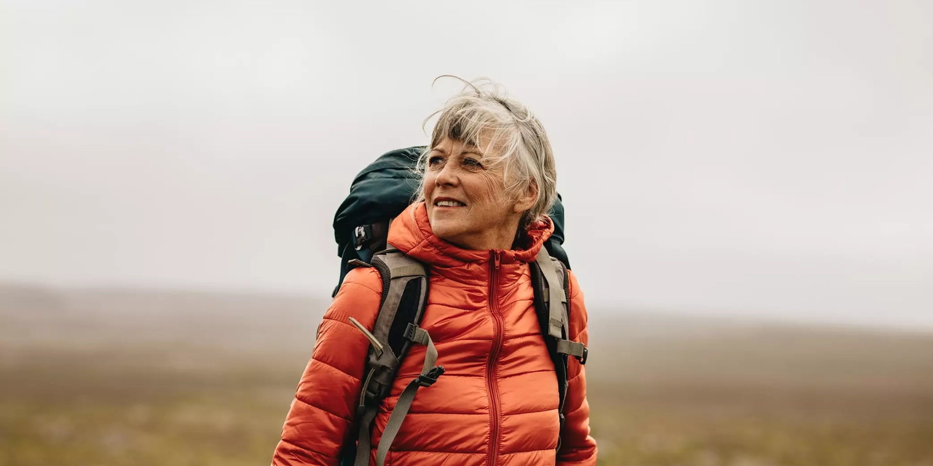 Vrouw tijdens het wandelen met rugzak in een open landschap.