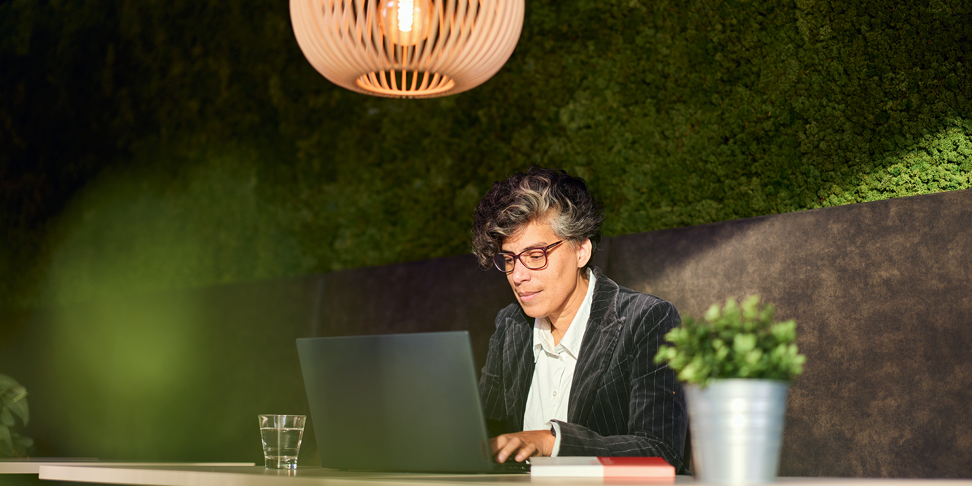 Vrouw werkt achter laptop in groene kantooromgeving